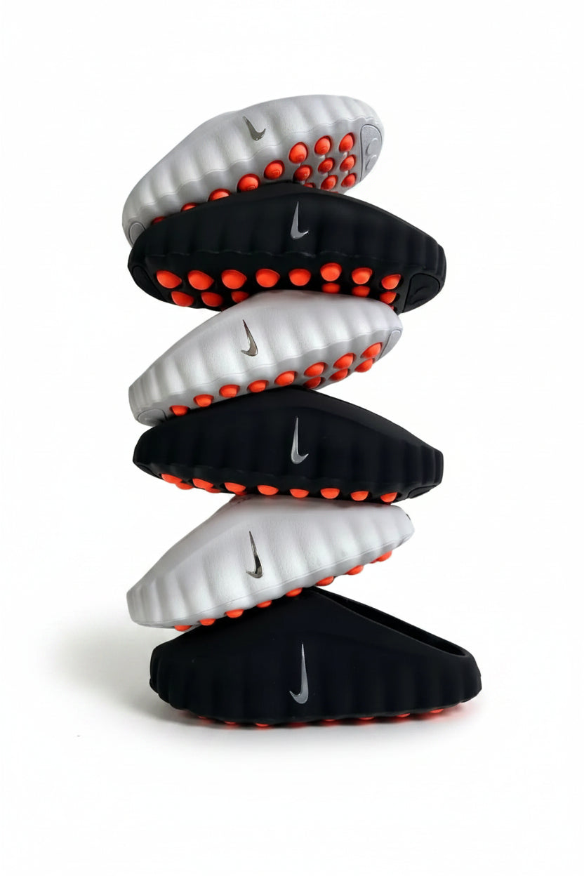 Stack of black and white sandals with red accents on a light gray background